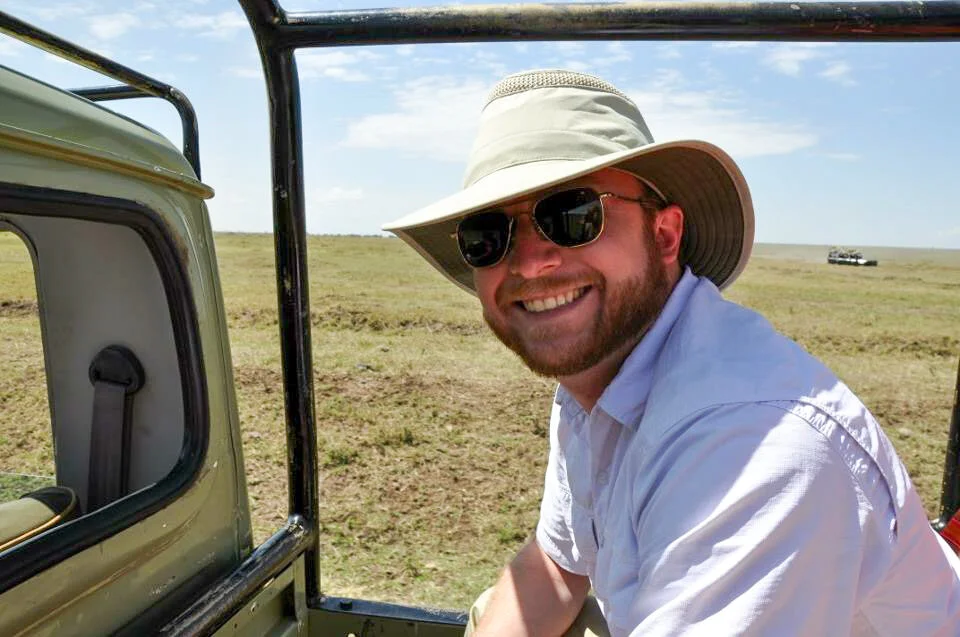 Smiling man wearing sunglasses and a sun hat outdoors