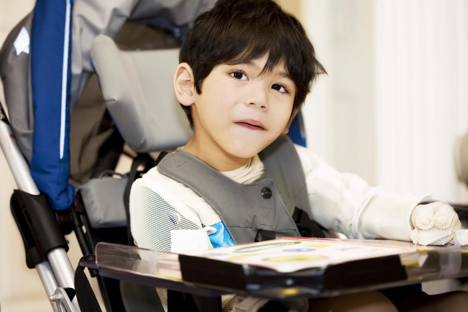 Child seated in a wheelchair with a communication tray