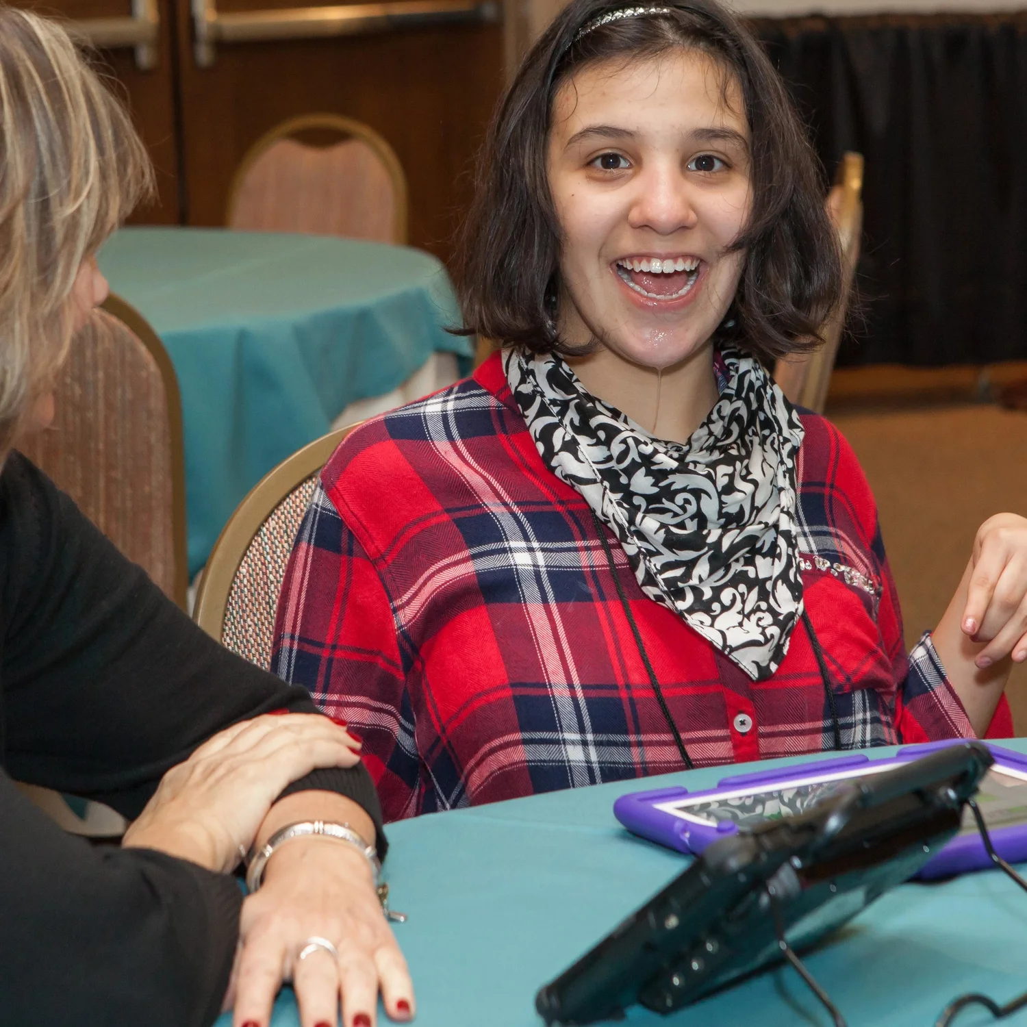 Woman smiling while using a tablet-based communication aid