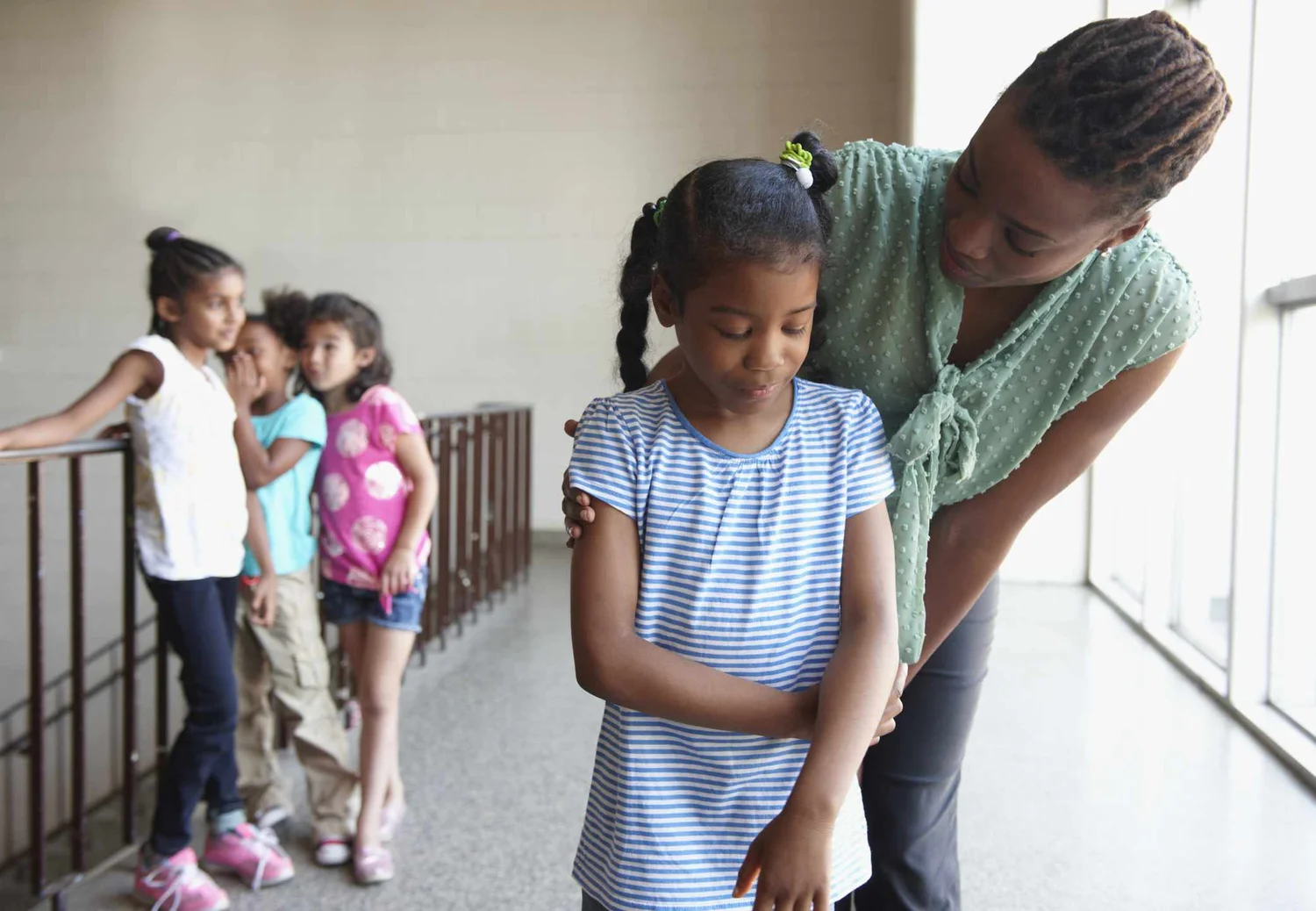 Teacher comforting a child while classmates stand in the background