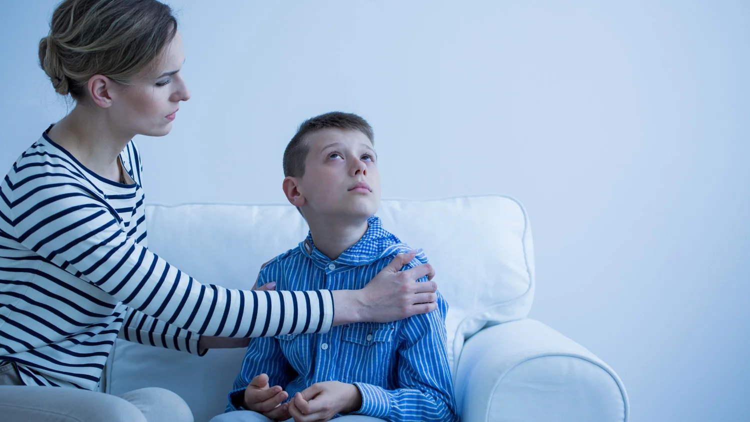 Adult speaking face-to-face with a young boy on a sofa
