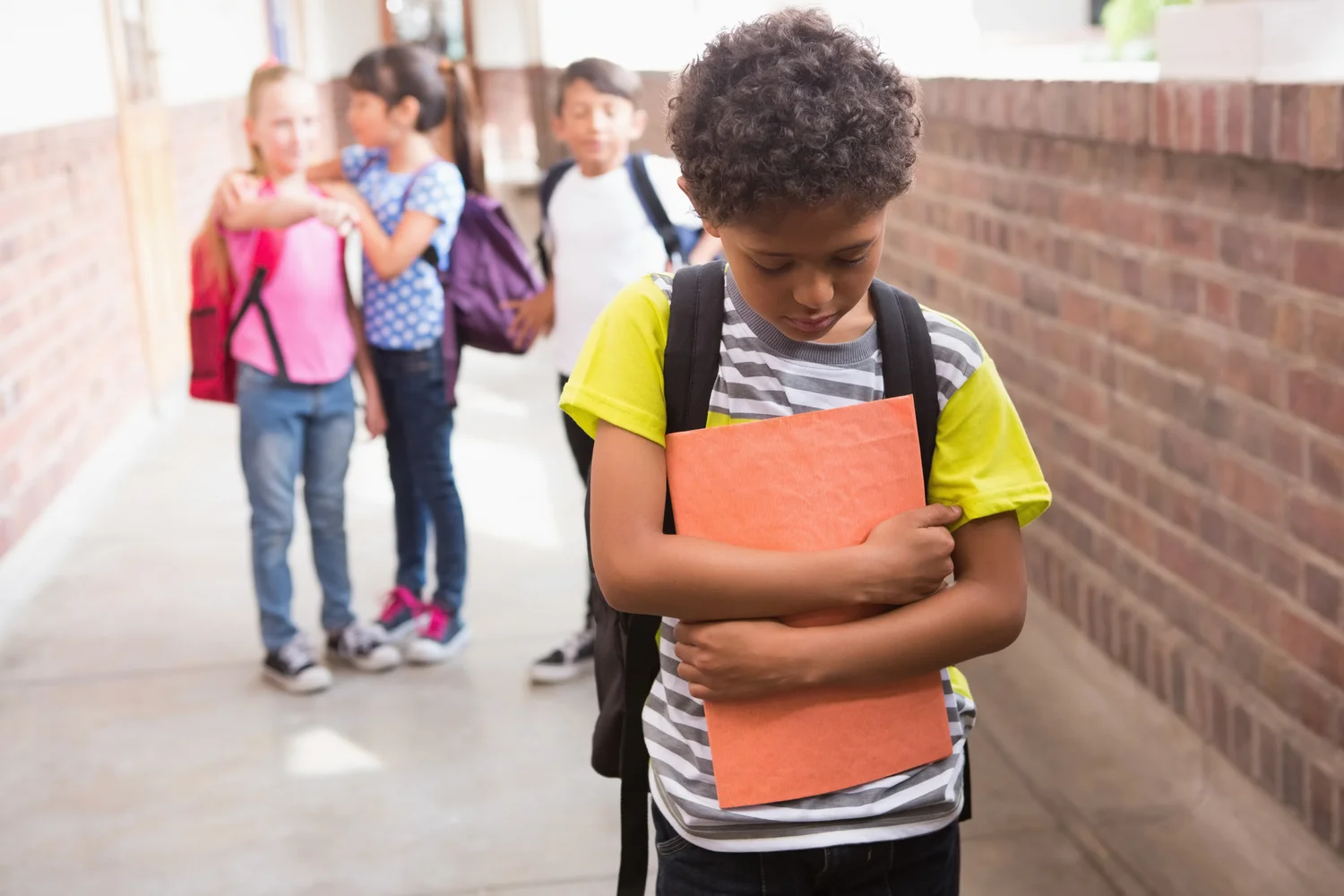 Student standing apart from classmates in a school hallway