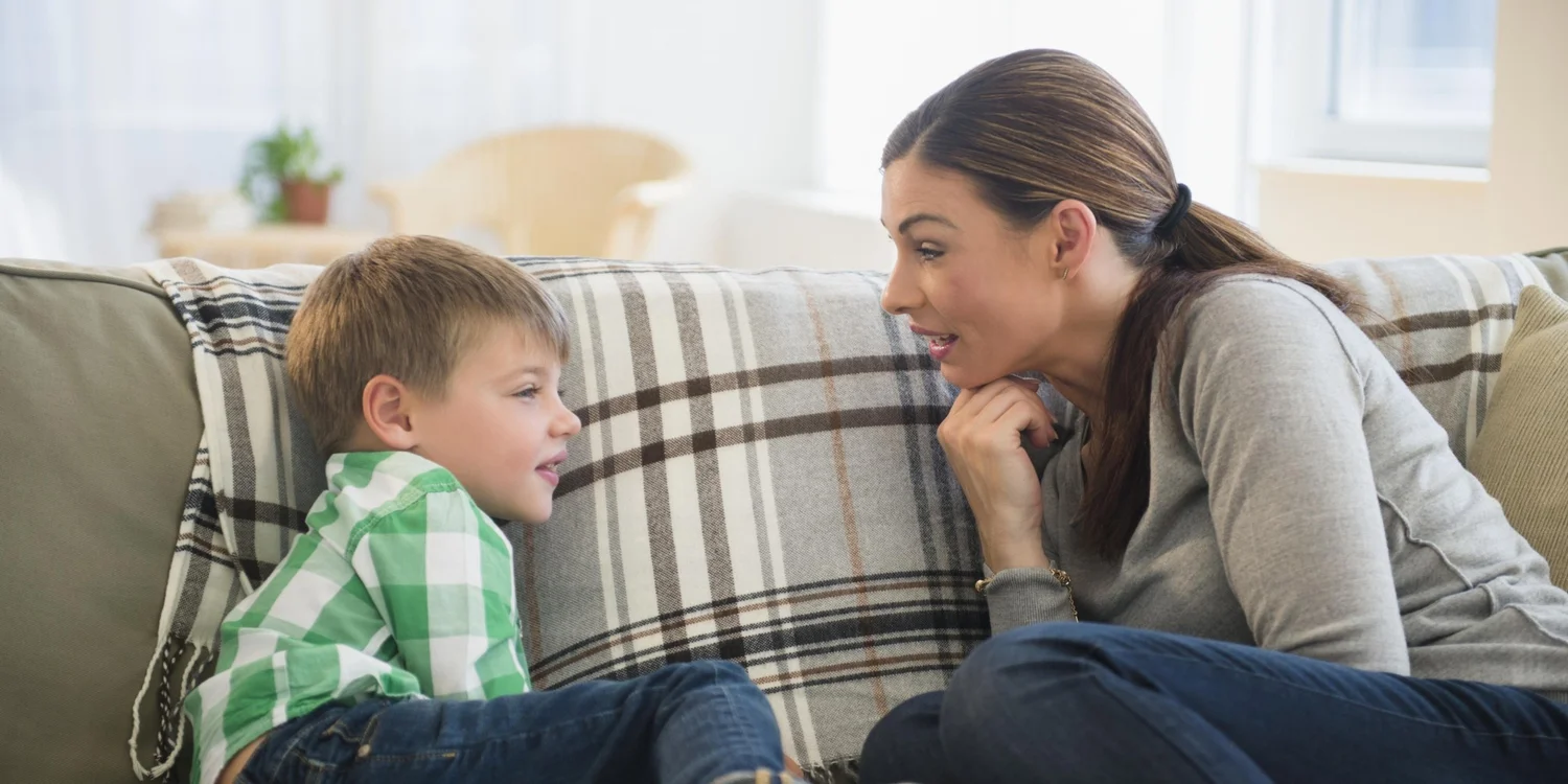Mother talking face-to-face with her son on a sofa