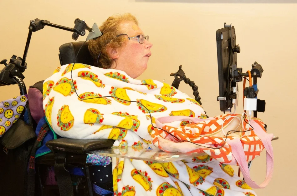 Woman in a wheelchair using a mounted tablet communication device