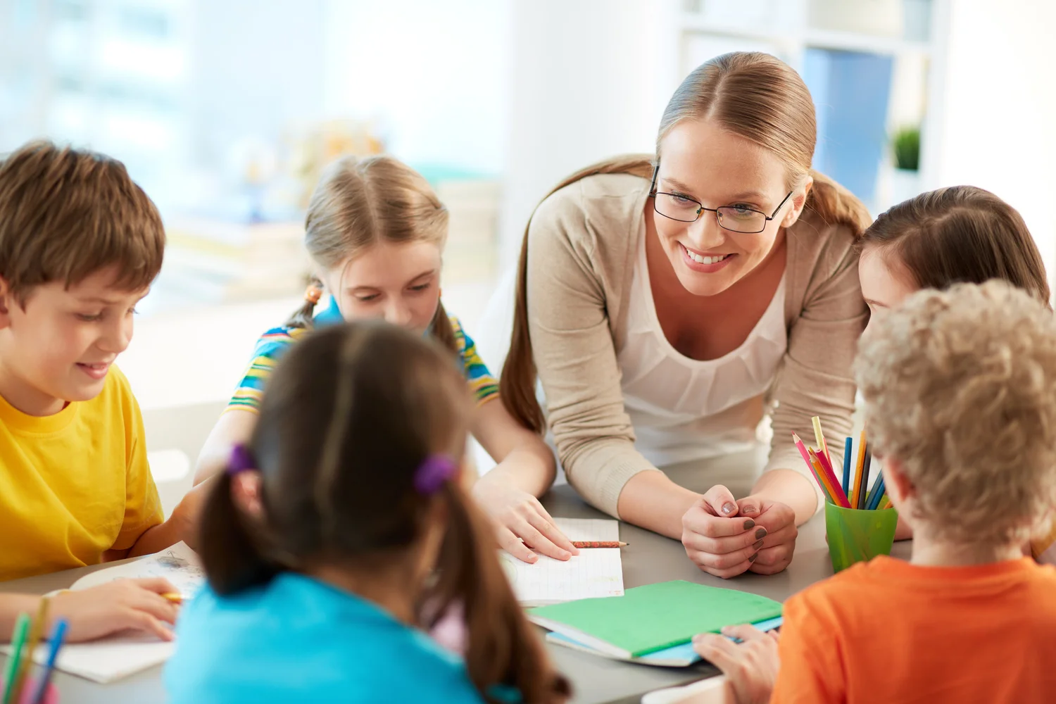 Teacher seated with children during a classroom activity